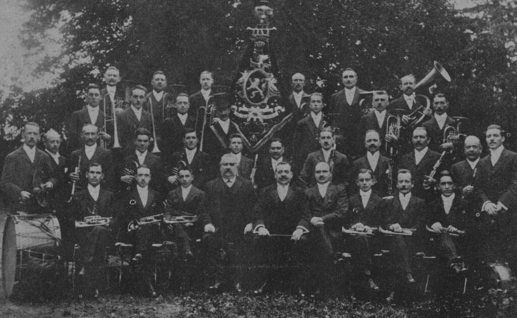 Les membres de la royale harmonie réunis autour de leur drapeau avec leurs instruments en main.